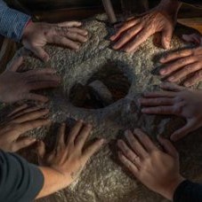 six sets of hands in a circle on the ground