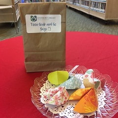 paper fortune cookies on a plate, alongside paper bag with Teen Grab-n-Go label