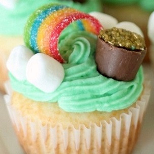 vanilla cupcake with green icing, mini marshmallows and rainbow fruit roll-up