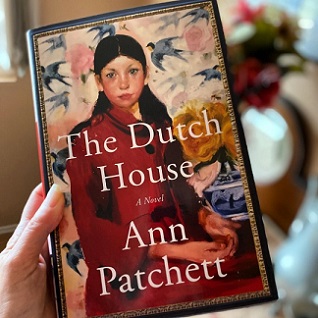 a hand holding a copy of the book The Dutch House