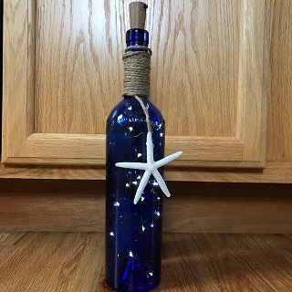 blue wine bottle with LED lights inside and a starfish attached