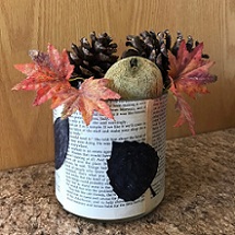 vase covered with book pages and black leaf silhouettes