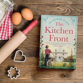 book titled "The Kitchen Front" on a cutting board with a rolling pin, eggs and cookie cutters