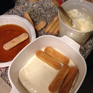 casserole pan with layer of white filling and four lady fingers layered over that, container of filling on the side