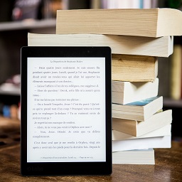 kindle leaning up against 9 stacked books