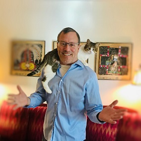 man in blue button down shirt, with a cat on his shoulders