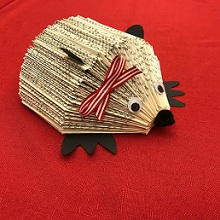 recycled book cut and folded to look like a hedgehog, with googly eyes and black paper feet