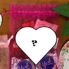 white heart with black "?" in the middle superimposed over photo of gift bag