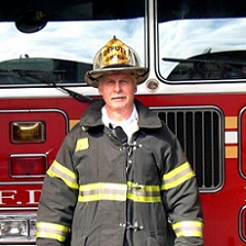 Man in firefighter gear posed in front of a fire truck