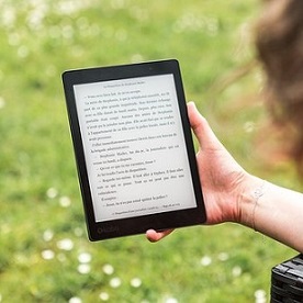 woman reading with kindle in park