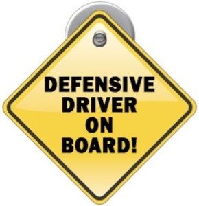 Yellow car sign with words "Defensive Driver on Board"