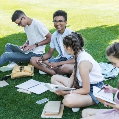 teens siting on lawn writing in notebooks