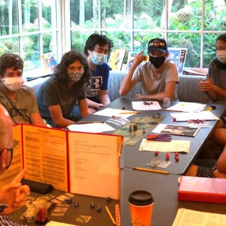 five teens around a table playing Dungeons and Dragons