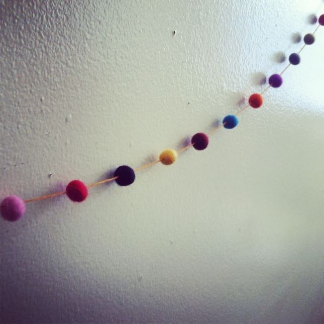 colorful pompom garland hanging on wall