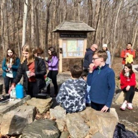 teens sitting on rocks enjoying donuts and cider