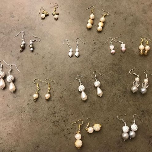 Twelve pairs of hand-made earrings displayed on a table