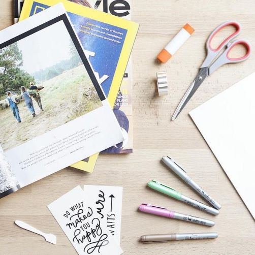 magazines, cut out words, colored pens, scissors and glue stick on a table top