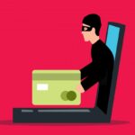 cartoon of thief emerging from laptop screen holding a credit card