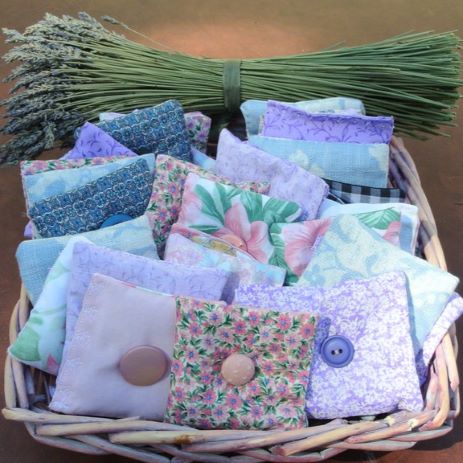 colorful sachets in a basket, with a bunch of cut lavender on the side