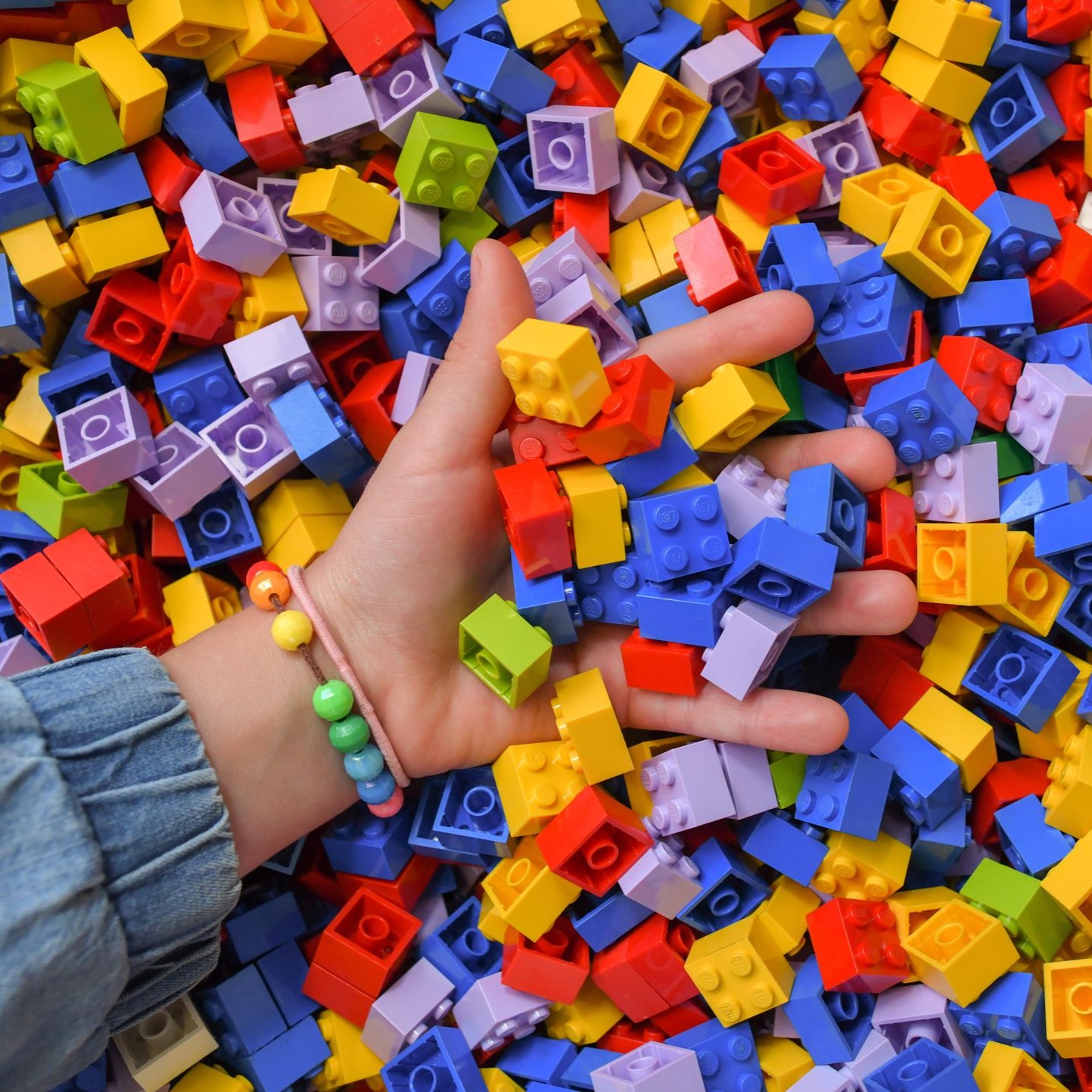child's hand in a pile of Legos