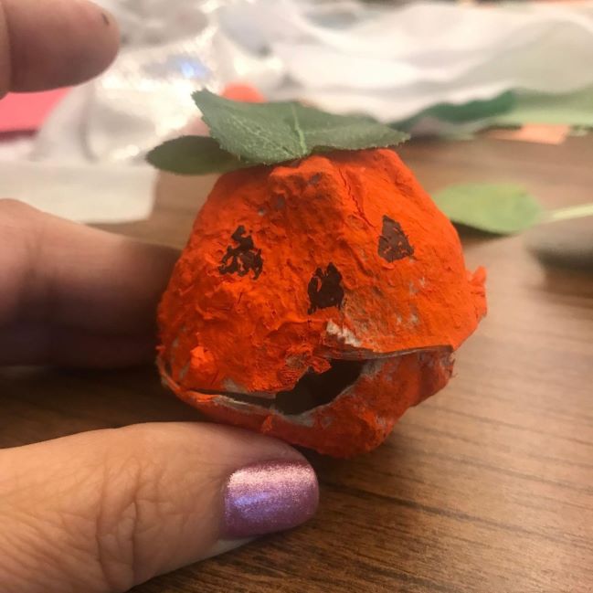 single egg cup from carton decorated as an orange pumpkin