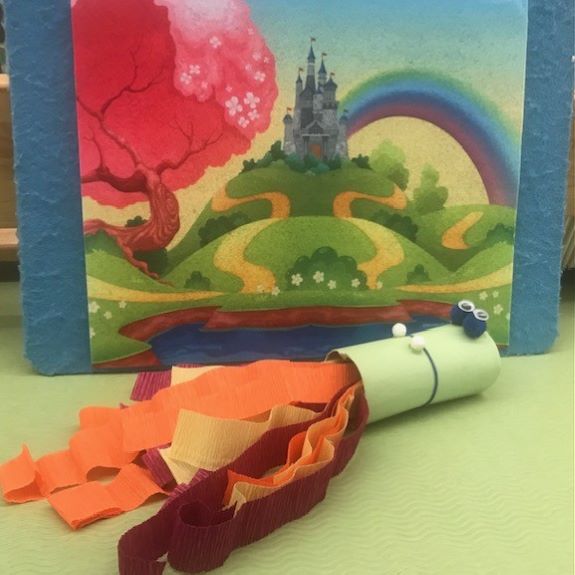 cardboard tube decorated to look like a dragon with yellow and orange streamers coming out of mouth