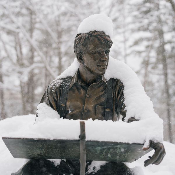 Outdoor statue of poet Robert Frost, covered in snow