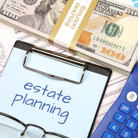 bundle of cash next to clipboard with Estate Planning written on it