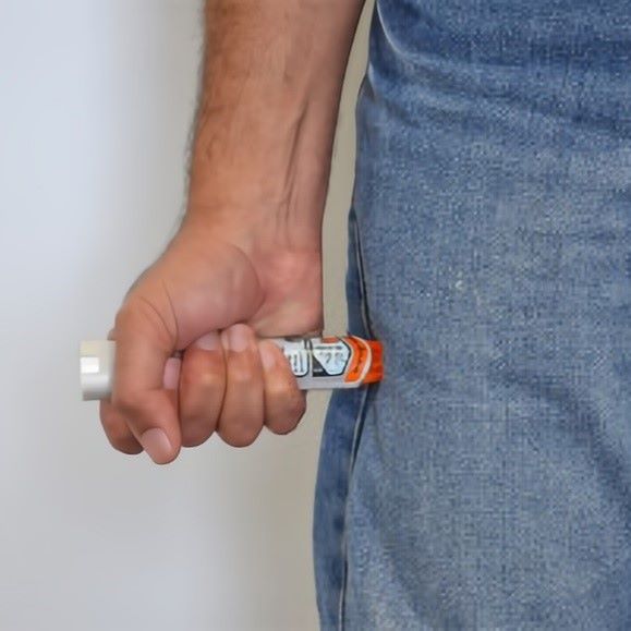 a hand gripping an epipen to jab into thigh
