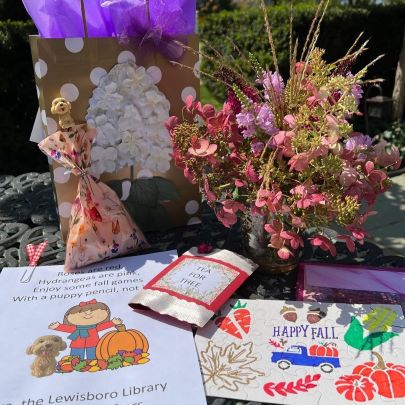 flowers in vase next to autumn scene puzzle and gift bag