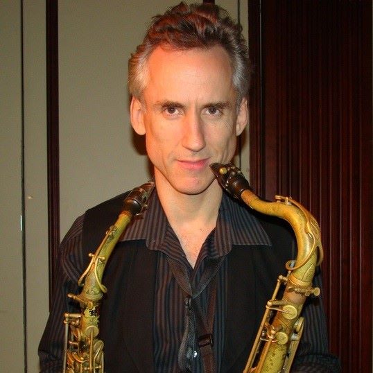 man holding two saxophones