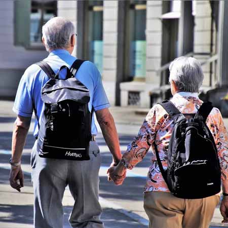 Older couple with backpacks walking away from camera