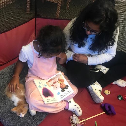 parent and child reading alongside a kitten