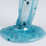 blue tinted slime with embedded snowflakes, being poured onto hard surface