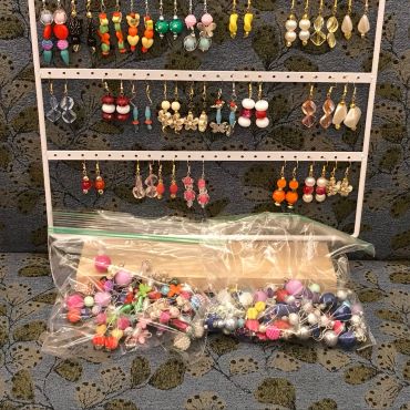 assorted hand-made earrings hanging on an earring holder display