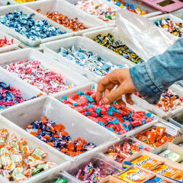 hand reaching into a bin of candies, separated into types by dividers