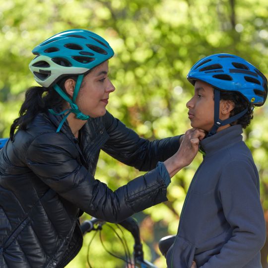 woman wearing bike helmet putting helmet on her child