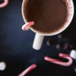 Cup of cocoa with mini candy canes and marshmallows sprinkled alongside