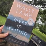 photo of hand holding a book titled "The River is Waiting"