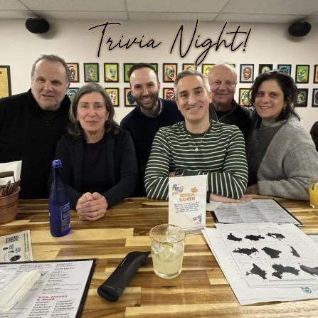six people posing for a photo while playing trivia night at a restaurant