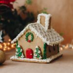 gingerbread house decorated with white icing and green and red wreaths