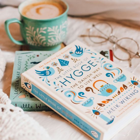 book titled "The Little Book of Hygge: the Danish Way to Live Well" alongside a cup of coffee