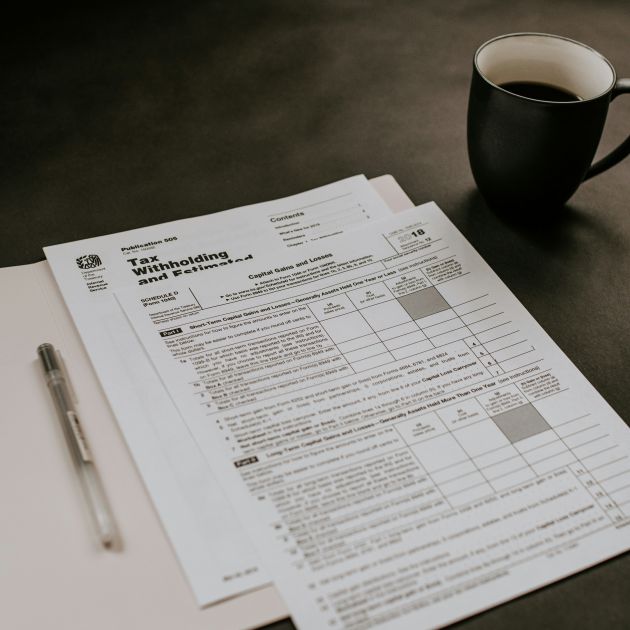 tax forms on a table beside a pen and a cup of coffee