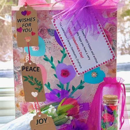 gift bag decorated with flowers and hearts, alongside bouquet of roses