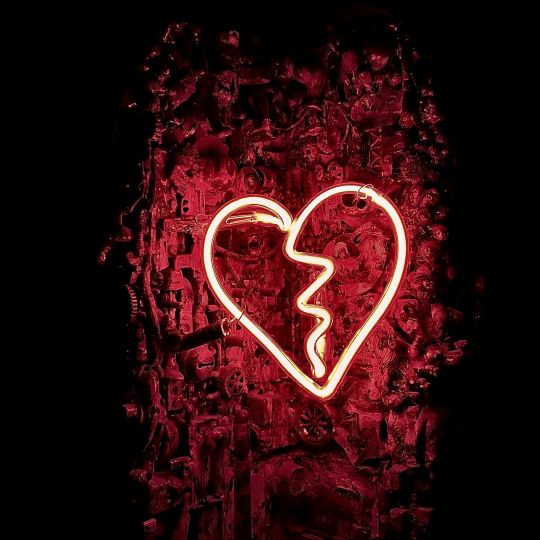 white neon light shaped like a broken heart, set against a deep red background