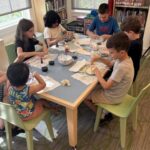 6 children sitting at a table working on a science experiment