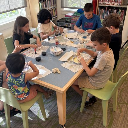 6 children sitting at a table working on a science experiment