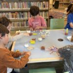 children sitting at a table building structures out of toothpicks and mini marshmallows.