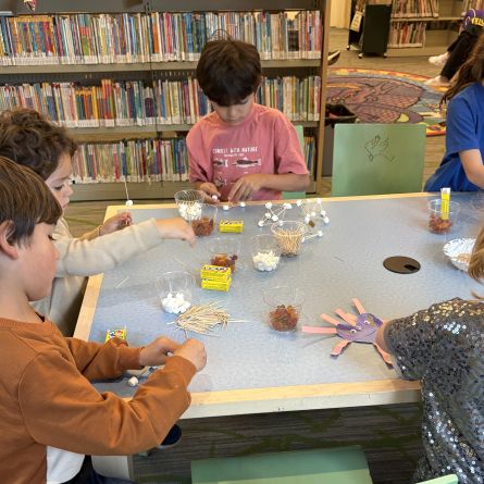 children sitting at a table building structures out of toothpicks and mini marshmallows.