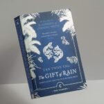 Blue book jacket with title The Gift of Rain in white lettering, surrounded by white illustrations of fish and vegetation